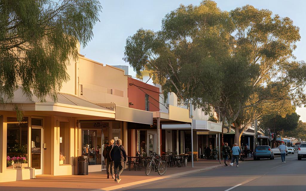 A regional New South Wales main street in morning light, with shopfronts and residents walking along the footpath